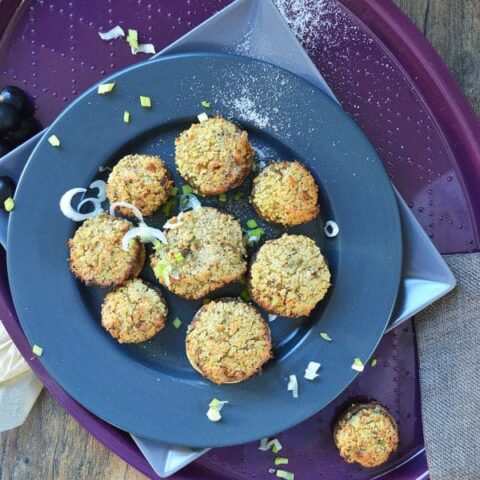 Mushrooms stuffed with couscous on a navy plate on a purple tray