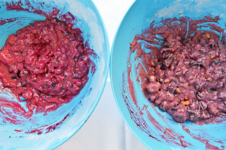 Two blue bowls, one with pink cookie batter, one with purple