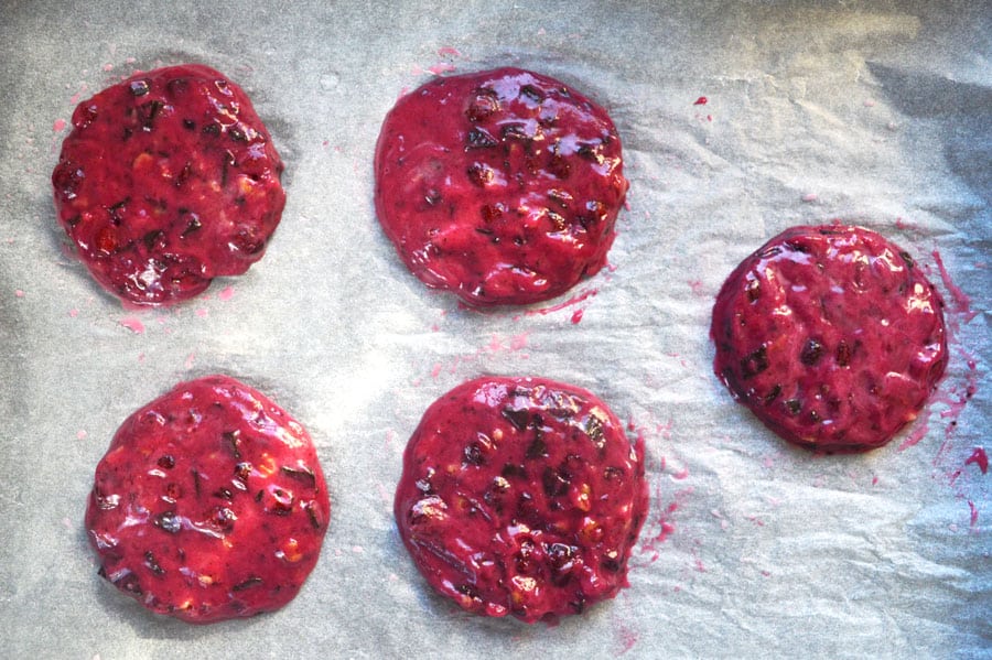 Round flattened pink cookie batter on baking paper