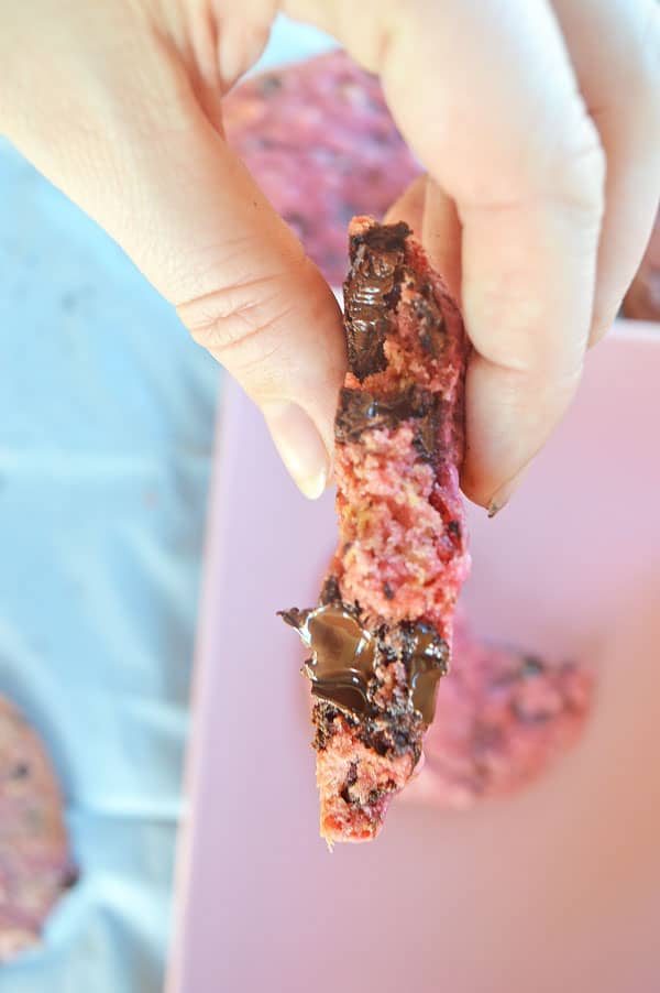 A picture of a snapped pink cookie with melted chocolate chunks