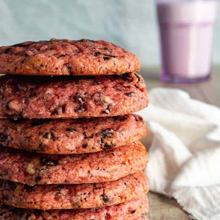 A stack of seven pink cookies with chunks of chocolate and walnut