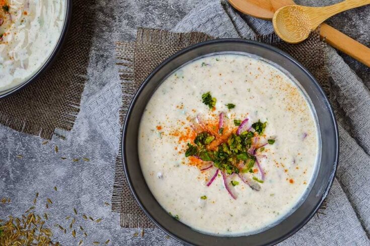 Two bowls of raita with red onions and cilantro on top