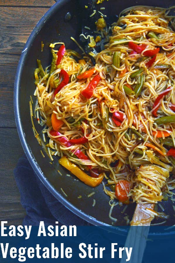 A large black pan with stirfried vegetables and noodles