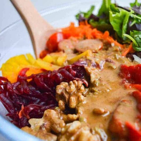 A close-up of a mixed salad with a creamy brown dressing