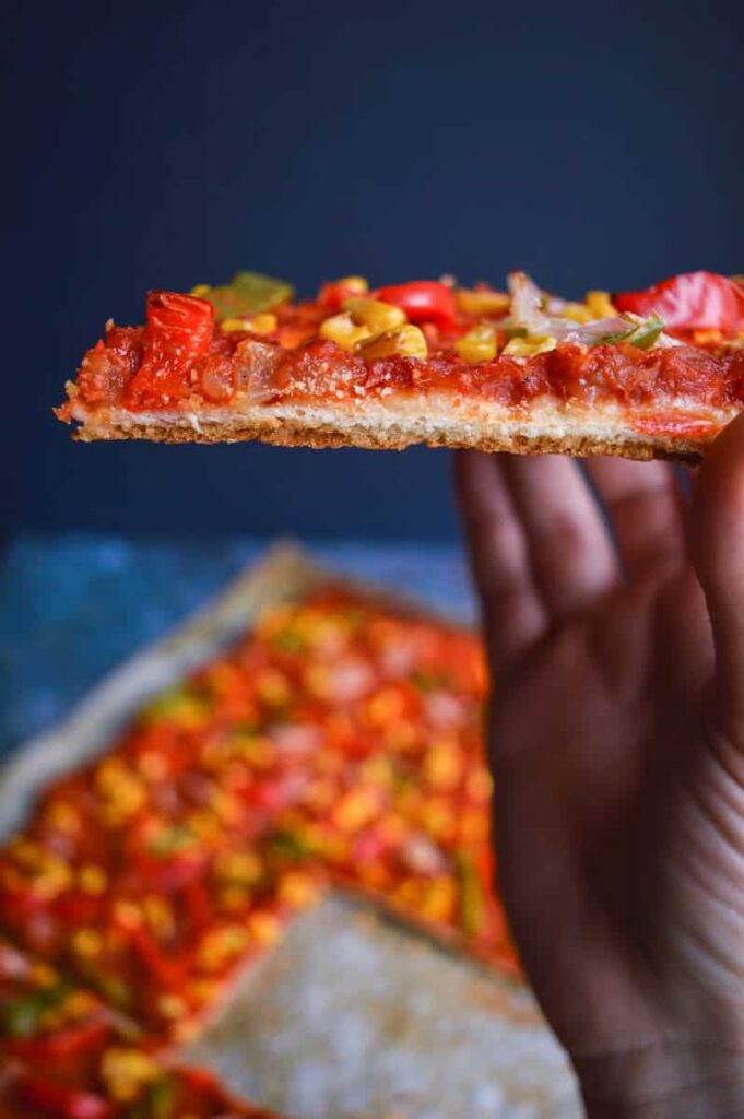 A thin crispy pizza slice viewed head on