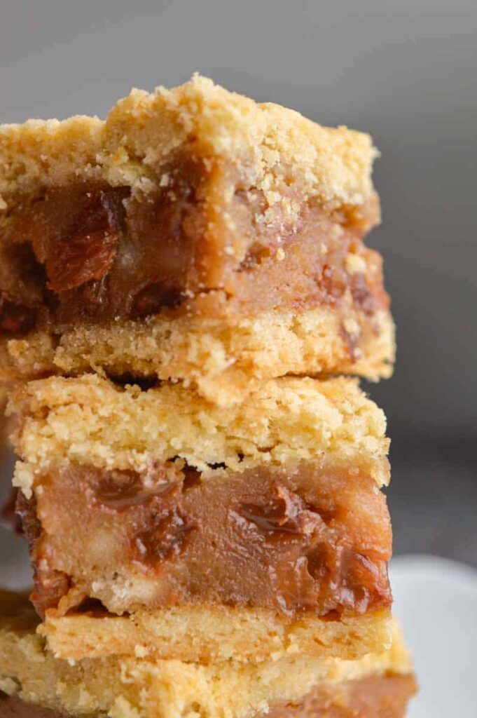 A close up of two pieces of shortcrust pastry sandwiching a brown raisin filling