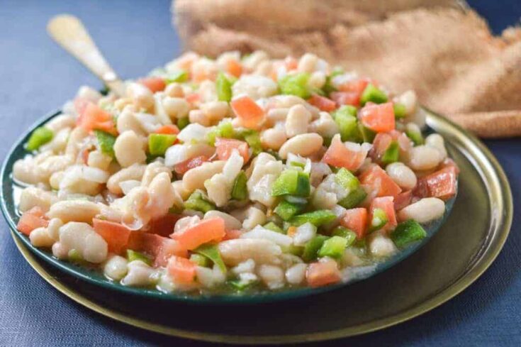 A plate of white bean salad with tomatoes and green peppers