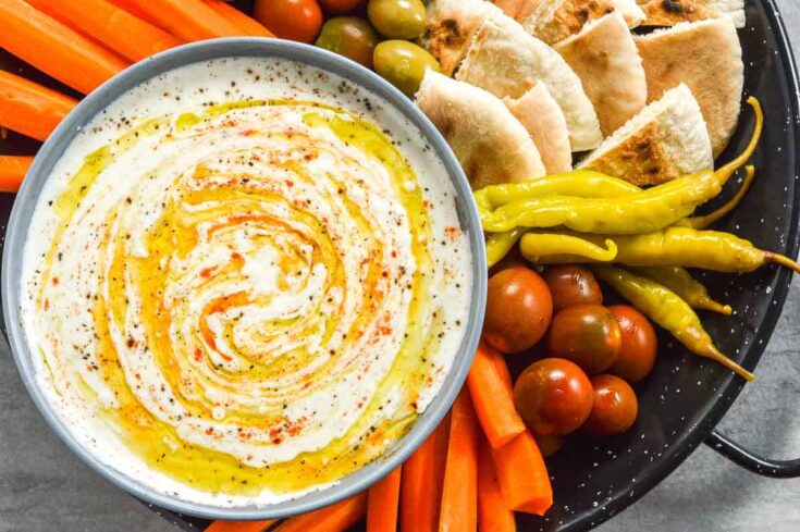 A bowl of feta do[ with chili peppers, carrots and pita