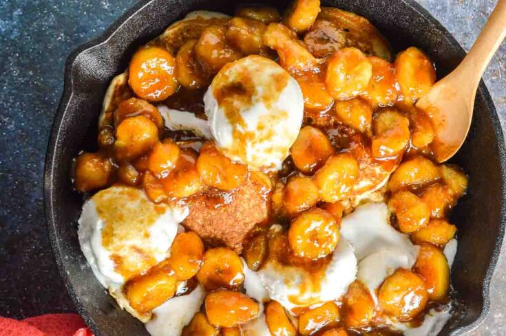 A black pan with ice-cream and saucy bananas