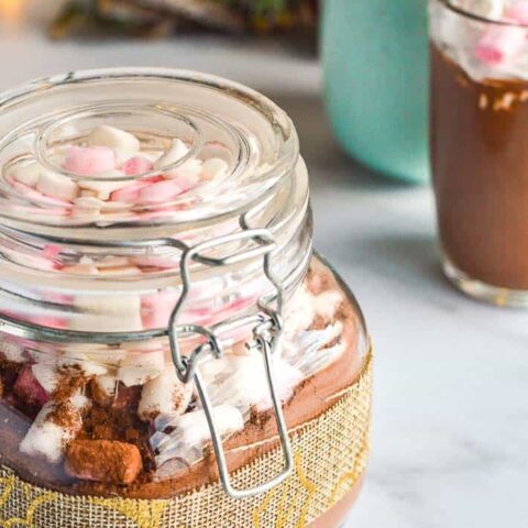 pickling jar filled with brown powder and marshamallows with two cups in the background
