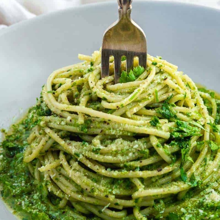 A fork stuck in a nest of green spaghetti