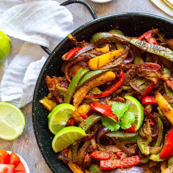 Black cast iron pan with peppers onions and limes