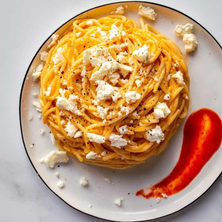 Top down view of a plate with a nest of spaghetti and feta on it
