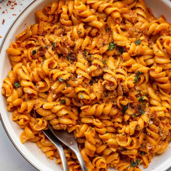 white pan with orange saucy pasta on a white background.