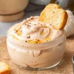 Square close up of pink-orange thick sayce in a glass jar with toasted bread stuck in it.