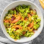 A grey bowl with mixed salad including lettuce, corn, tomatoes and olives.