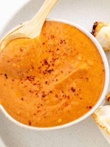 A bowl of thick orange sauce sprinkled with red pepper flakes.