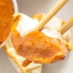 Pinterest image with chopsticks holding a gyoza dipped in orange sauce and text "spicy miso sauce" at the top and "thefieryvegetarian.com" at the bottom.