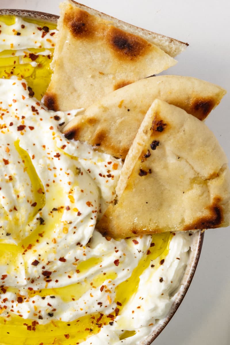 Close-up of a thick white liquid with red chilli flakes and golden oil sprinkled over.